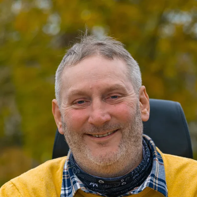 Steven Webb, smiling, outdoors on an autumn day